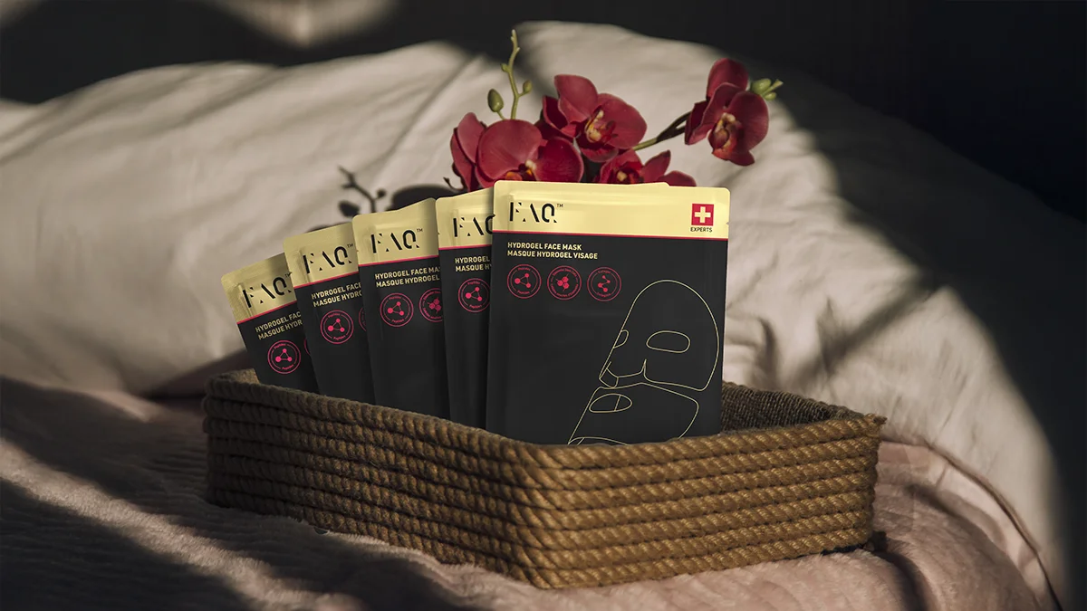 FAQ Hydrogel Glass Skin Face Mask sachets in a woven box on a comfortable bed
